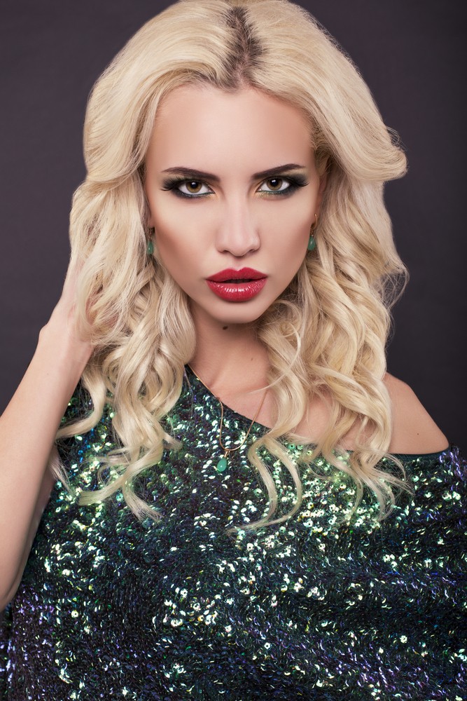 fashion photo of beautiful sexy model with blond hair in elegant green dress posing at studio